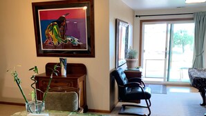 Un coin repas avec une table dressée pour deux personnes, un tableau accroché au mur et une vue sur l’extérieur grâce à une porte coulissante.