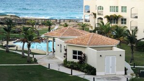 Un hotel sulla spiaggia con piscina, palme e vista sull'oceano.