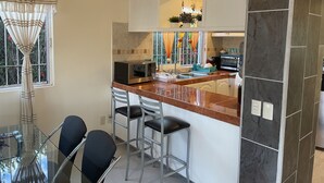 Una cuina moderna amb una illa central, tamboretes d'esbarjo, microones i torradora.