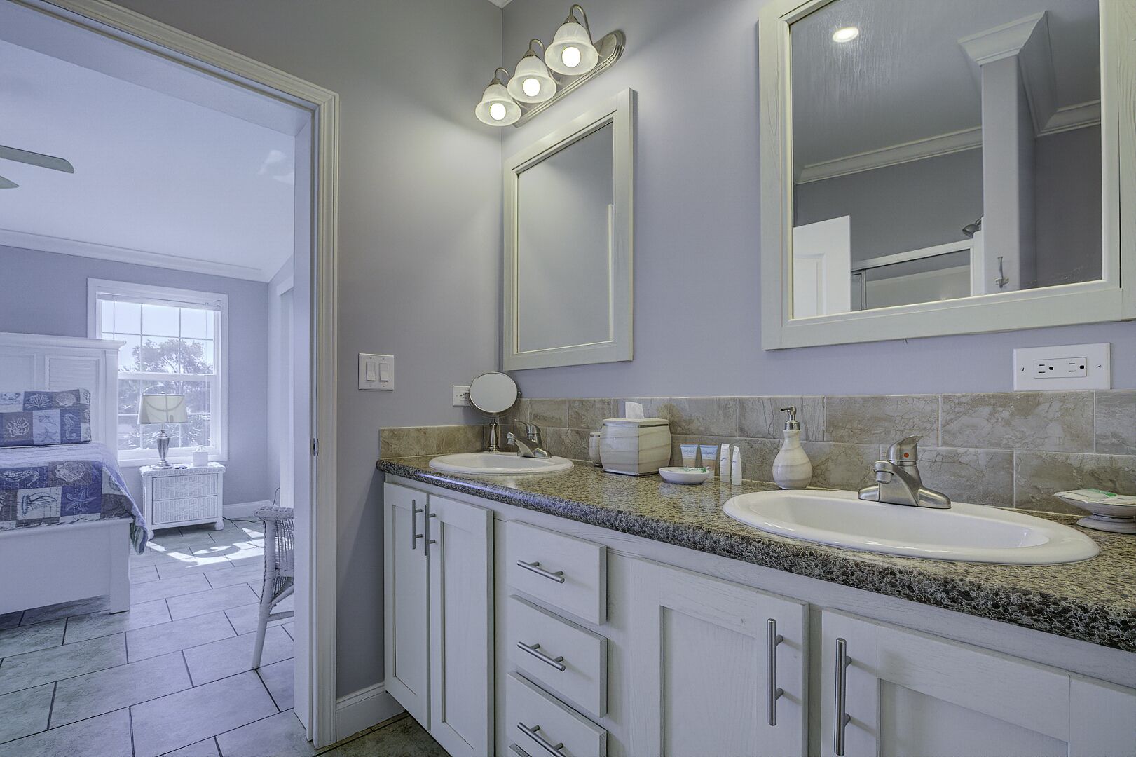 A modern bathroom with two sinks, a large mirror, and a vanity with drawers.