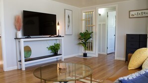 A living room with a flat-screen TV, a glass coffee table, a sofa, and a potted plant. - Casa Little Bird (Los Alamos)