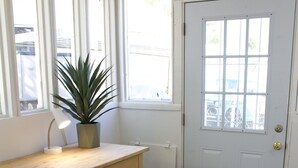 A room with a wooden desk, a potted plant, a white door, and a window with blinds. - Casa Little Bird (Los Alamos)