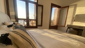 A bedroom with a bed, pillows, a desk, and a window. - 2 BR flat overlooking open lagoon and private pool (Red Sea Governorate)