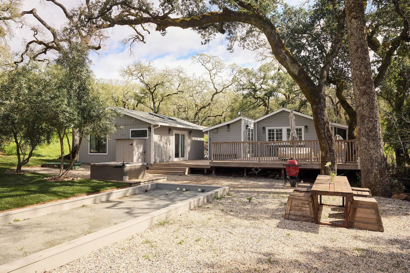 A cabin with a deck, outdoor seating, and a barbecue area.