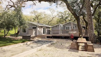 A cabin with a deck, outdoor seating, and a barbecue area.