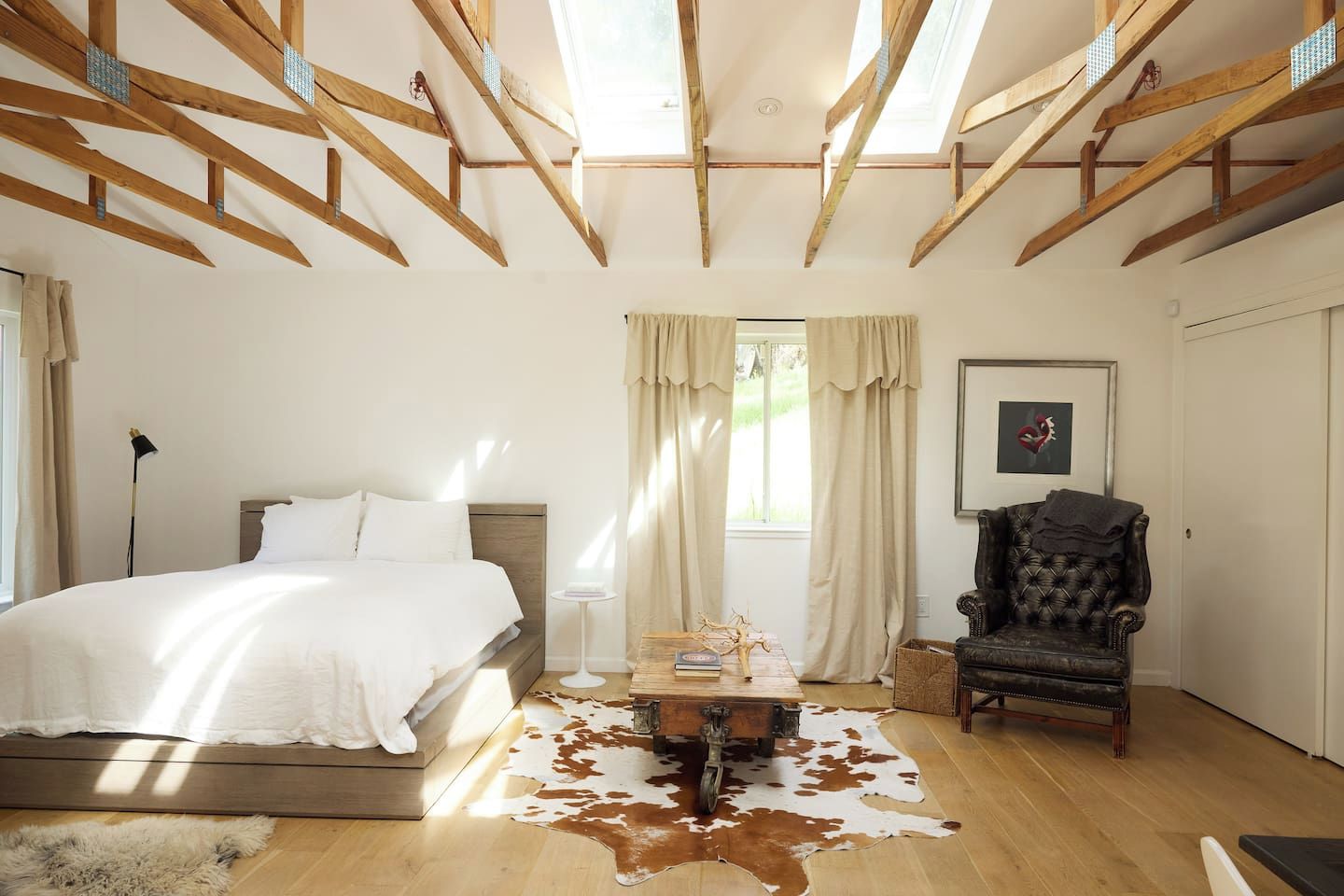 Quarto com cama, cadeira, mesa e tapete de couro de vaca.