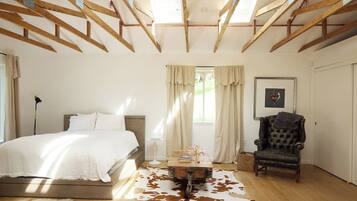 Quarto com cama, cadeira, mesa e tapete de couro de vaca.