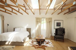 Quarto com cama, cadeira, mesa e tapete de couro de vaca.
