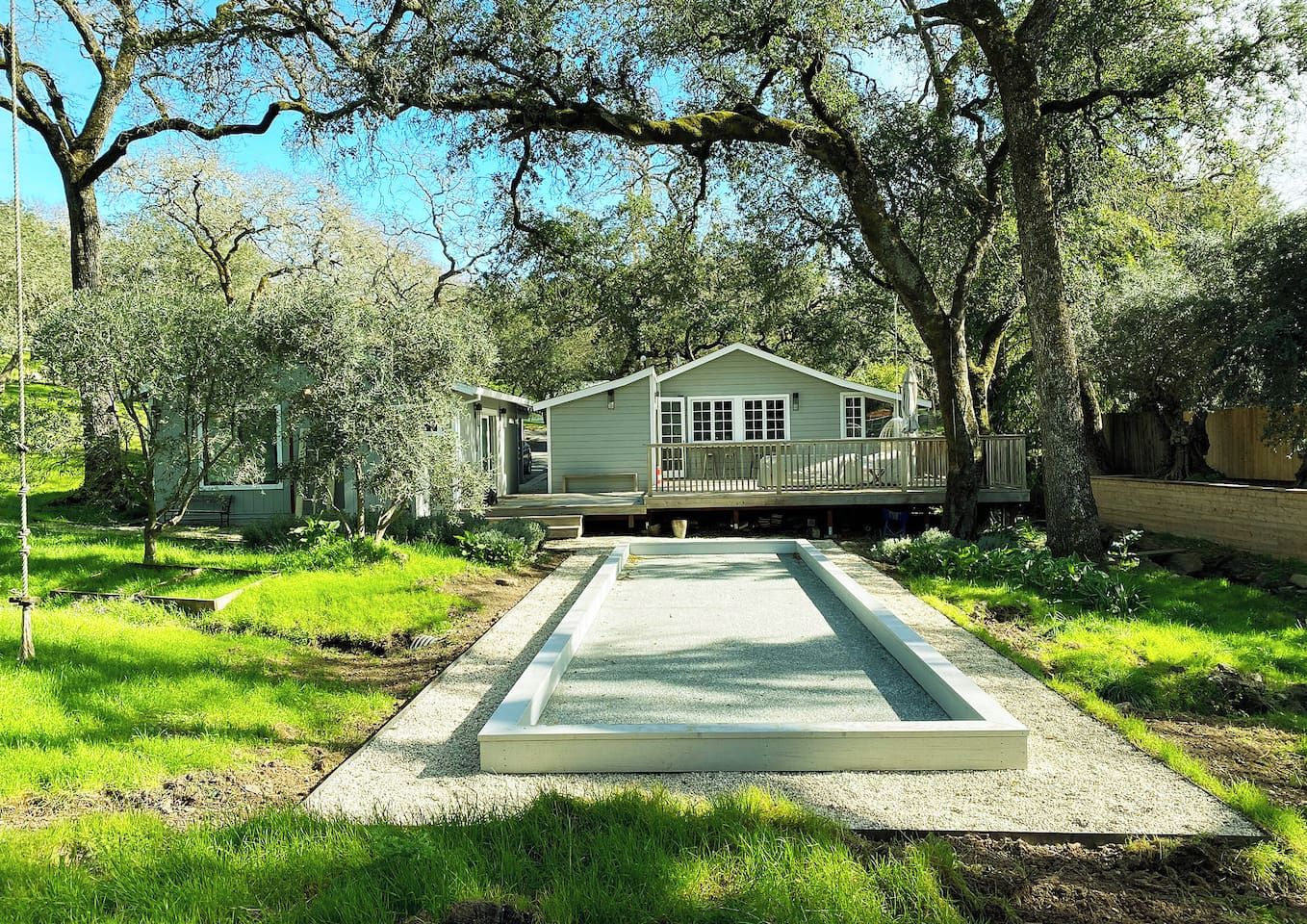 A house with a deck, surrounded by trees and a well-maintained lawn.