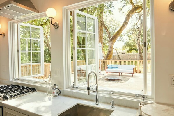 A kitchen with a large window, a gas stove, and a sink.