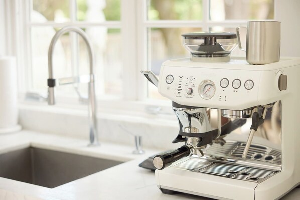 Une machine à café dotée d’un écran numérique, d’un réservoir d’eau et d’un porte-tasse.
