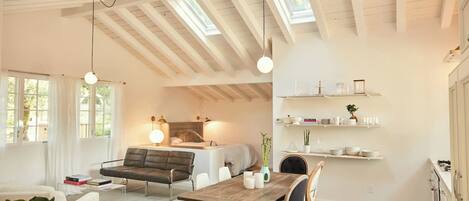 Un interior moderno con techo estilo loft, un área de comedor con mesa de madera y estanterías empotradas con utensilios de cocina.