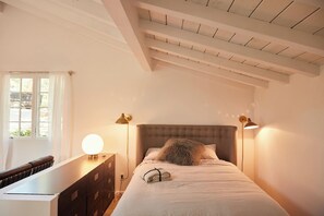 Une chambre à coucher avec un lit, des lampes de chevet, une commode et une fenêtre.