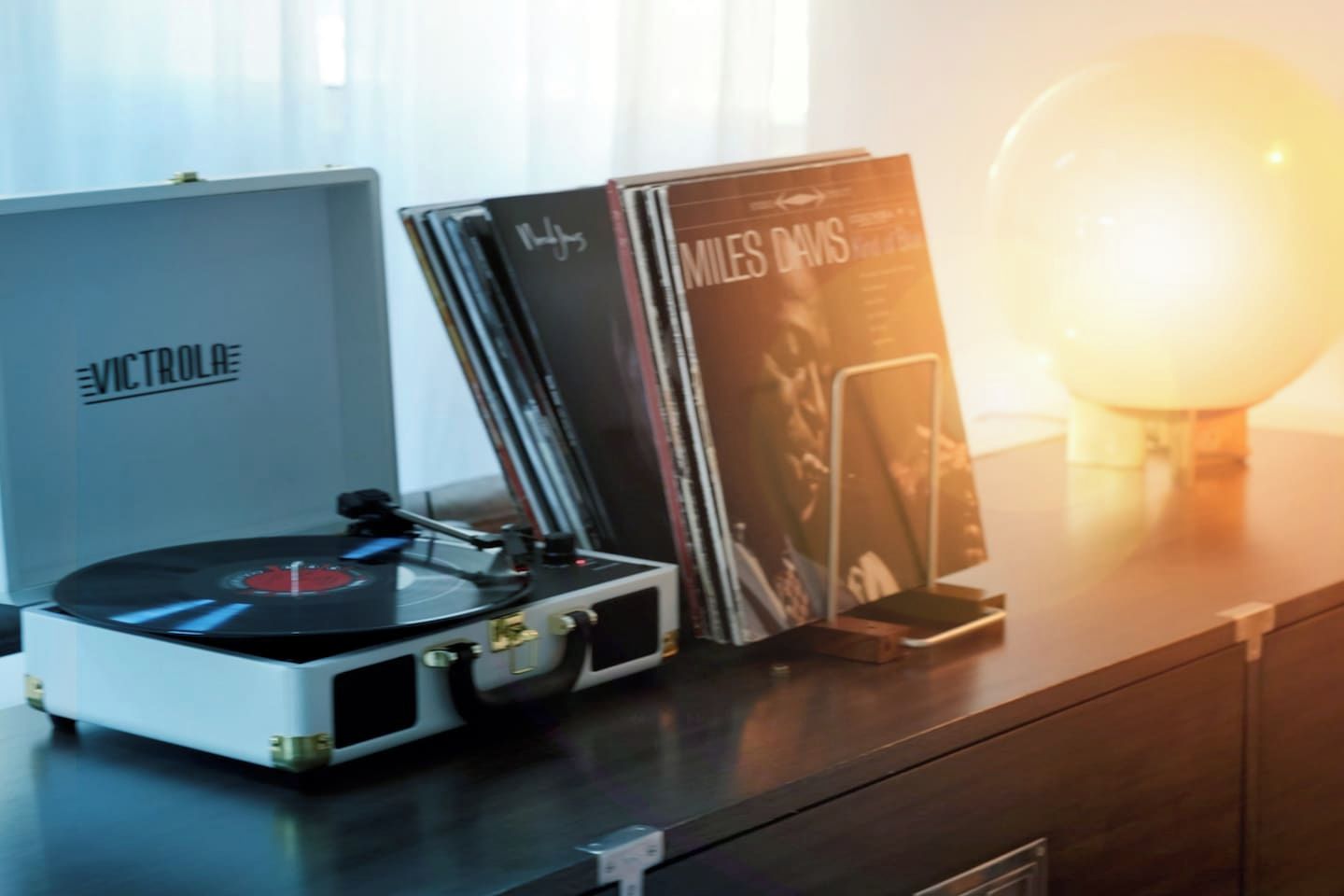 A turntable with vinyl records and a speaker on a wooden surface.