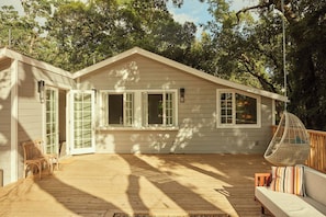 A wooden deck with a hanging chair and a cushioned seating area.
