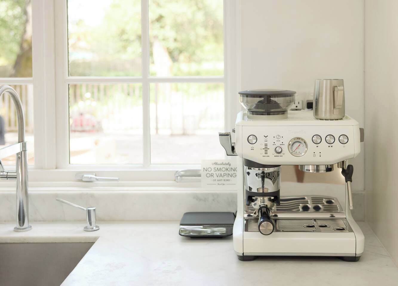 A coffee machine on a kitchen counter with a window in the background.