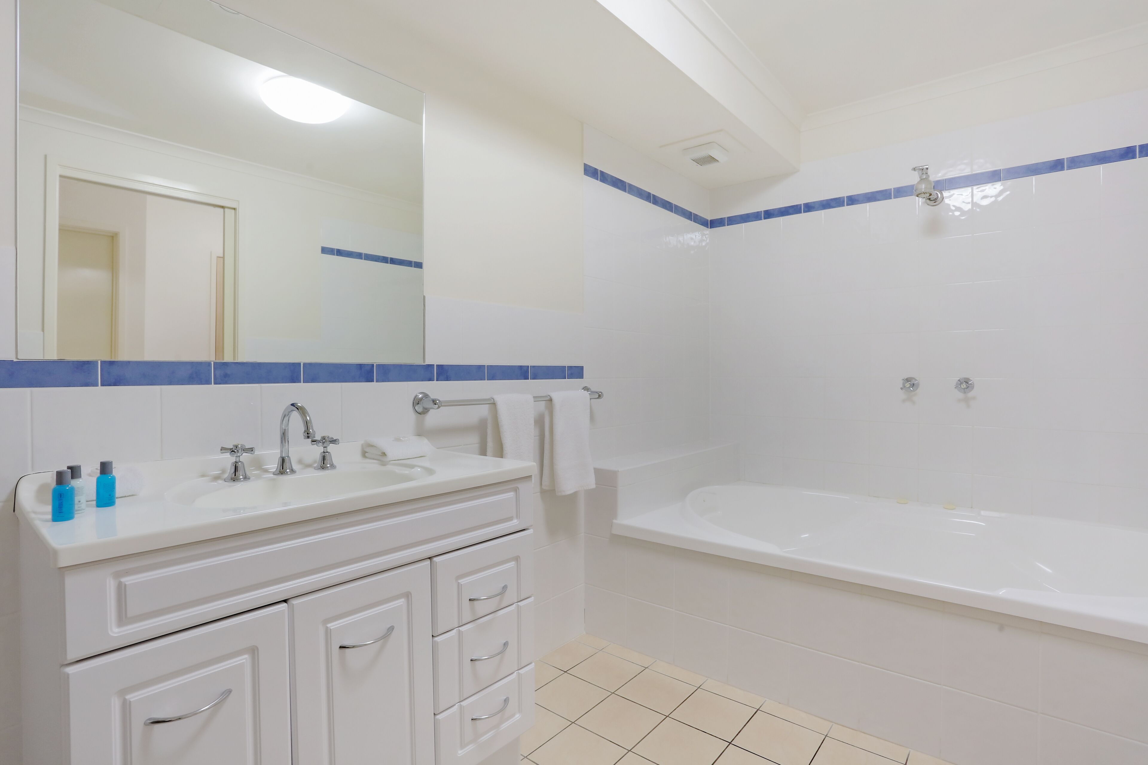 A bathroom with a white sink, mirror, and bathtub.