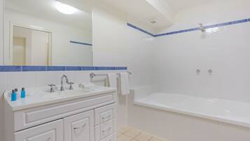 A bathroom with a white sink, mirror, and bathtub.