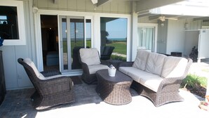 Un patio exterior con mobiliario de mimbre, que incluye un sofá, sillas y una mesa de centro.
