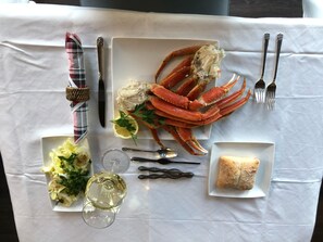 Una mesa dispuesta con langosta, ensalada, copa de vino, pan y cubiertos.