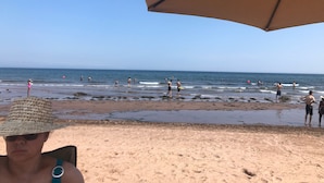 A beach scene with people swimming and standing in the water. - AUBERGE ET SPA LE HUARD (Chandler)