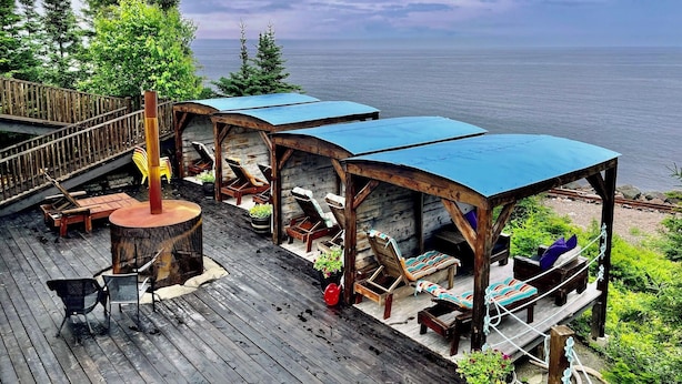 A wooden deck with outdoor seating and a view of the sea. - AUBERGE ET SPA LE HUARD (Chandler)