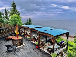 Una terraza de madera con mobiliario exterior y vistas al mar.