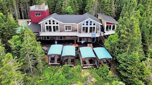 A large, multi-story house surrounded by dense forest. - AUBERGE ET SPA LE HUARD (Chandler)