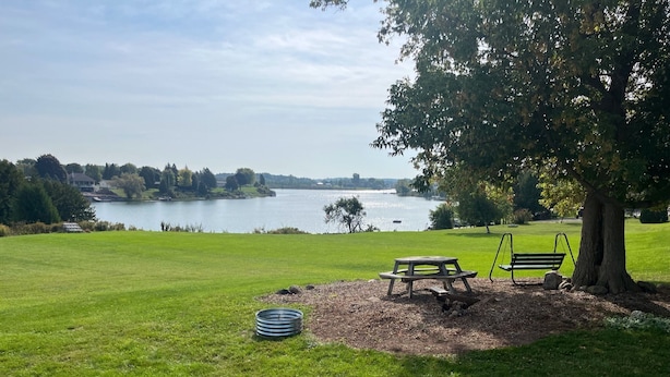 Ein Park mit Rasenfläche, einem Picknicktisch, einer Schaukel und einer Bank.
