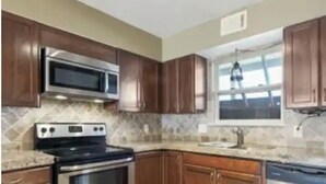 A kitchen with wooden cabinets, a stainless steel stove, a microwave, and a dishwasher. - Lovely 2 Bedroom condo with marina view and pool (Seabrook)
