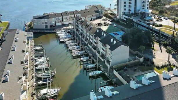 A marina with boats docked, a building with multiple floors, and a pool area with lounge chairs. - Lovely 2 Bedroom condo with marina view and pool (Seabrook)
