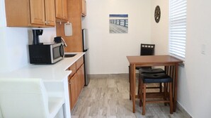 A compact kitchen with wooden cabinets, a microwave, a coffee maker, and a small dining table with two chairs. - WoW!! Stunning 1 BR // Prime Singer Island (West Palm Beach)
