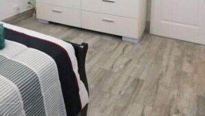 A bedroom with a bed, a dresser, a TV mounted on the wall, and a door. - WoW!! Stunning 1 BR // Prime Singer Island (West Palm Beach)