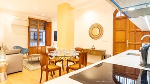 A modern living room with a dining area, wooden furniture, and a kitchen with a built-in stove. - Apto Catedral. Lovely apartment with the best location in Central Granada. (Granada)