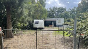 Zona amurallada con una caravana estacionada frente a un edificio con un letrero que dice 'BOX'.