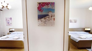 A hotel room with two beds, a painting of a coastal scene, and a wooden floor. - Holiday apartment with three bedrooms, terrace, air conditioning and car park (Umag)