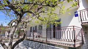 A building with a balcony, a tree in front, and a blue sign with the number 24. - Holiday apartment with three bedrooms, terrace, air conditioning and car park (Umag)
