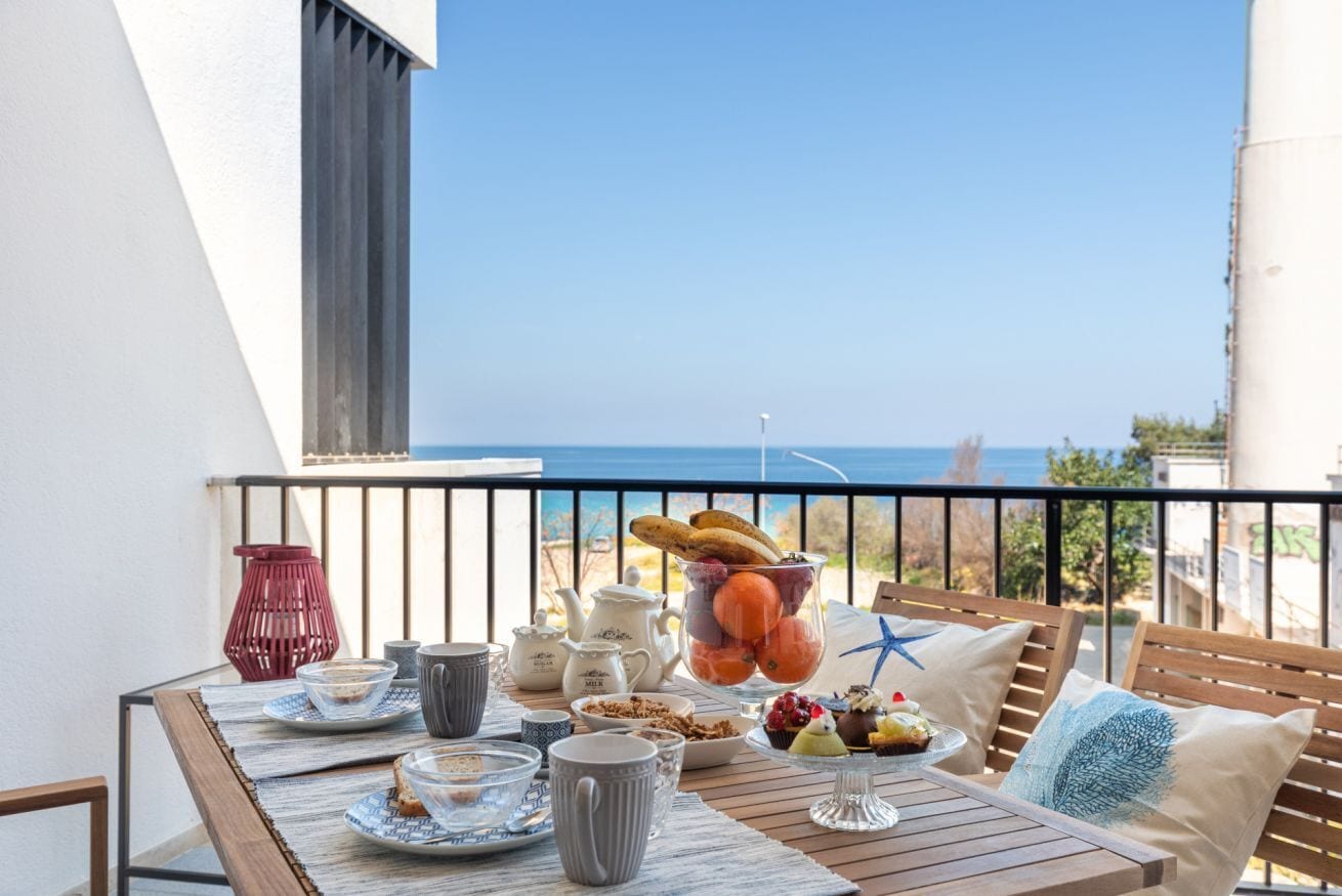 Un balcón con una mesa dispuesta para el desayuno, con vistas al mar.