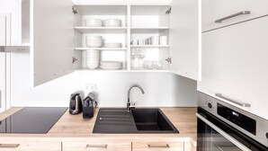 A modern kitchen with a black countertop, stainless steel appliances, and white cabinetry.
