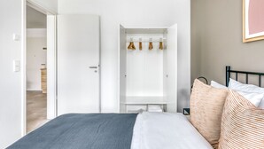 A bedroom with a bed, a wardrobe, and a bathroom visible through an open door.