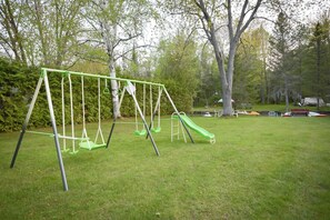 En gunga i en grönskande park med träd och ett tält i bakgrunden.