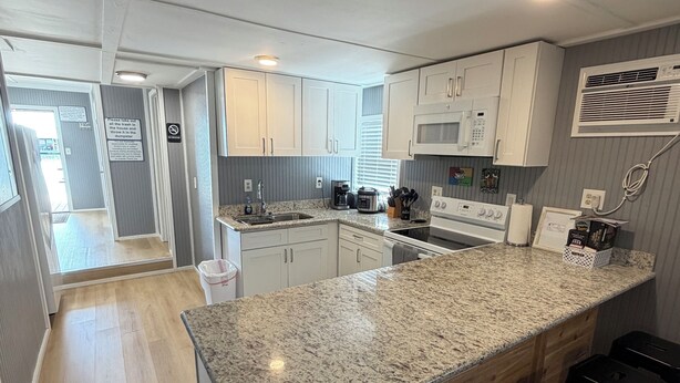 A modern kitchen with granite countertops, white cabinets, a built-in microwave, and a stainless steel sink. - Catfish house boat for rent, sleeps 8,Ice machine. perfect place to fish 🐠  (Venice)