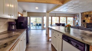 Una cocina amplia con vigas de madera, una isla central y vistas a un patio exterior.