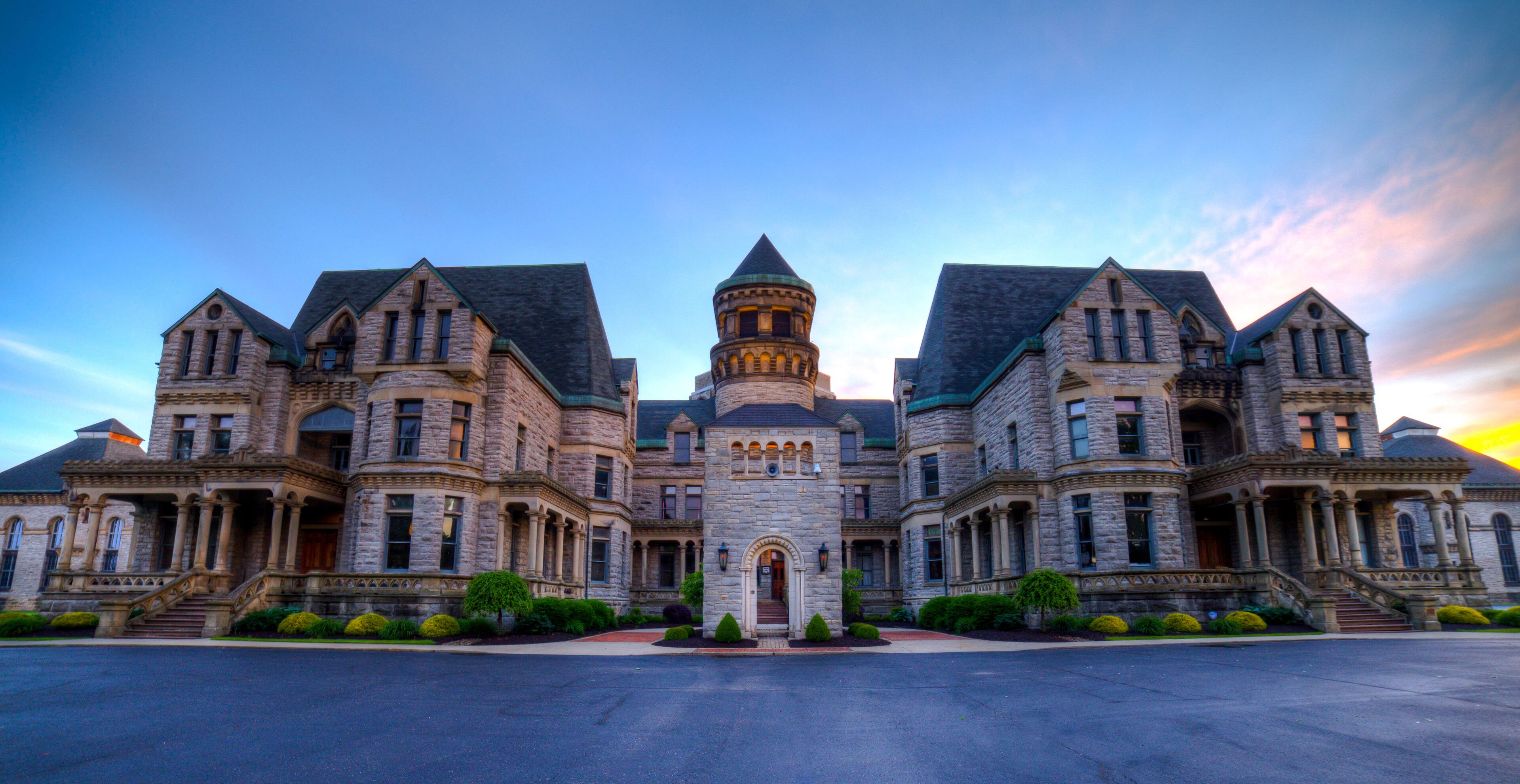 A large, historic stone building with multiple towers and a central entrance.