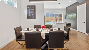Un comedor moderno con una mesa blanca, sillas negras y un centro de mesa con flores rojas.