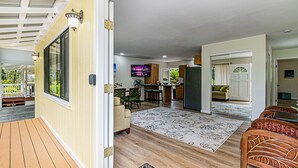A spacious living area with a wooden deck, a dining area with a TV, and a kitchen with a bar.