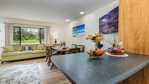 A modern living room with a sofa, dining table, and kitchen counter.