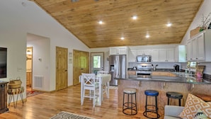 A spacious kitchen with wooden ceiling, white cabinets, and a central island with stools. - Hot Tub Relaxation & Mtn View: ‘Sky Blue Overlook’ (Marble)