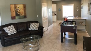 Un salon avec un canapé en cuir, une table basse en verre et une table de baby-foot.