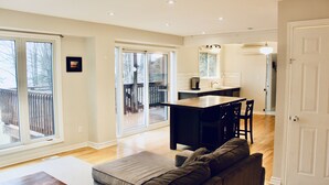 A spacious living area with a sofa, a coffee table, and a kitchen area with a dining table and chairs. - Beautiful lakefront retreat, 4 bedroom, sleeps 8 (Huntsville)